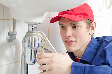 Plumber in uniform repairing old pipeline in the house.
