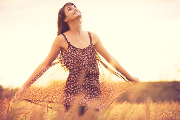 Romantic Model in Sun Dress in Golden Field at Sunset