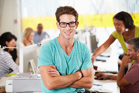 Portrait Of Man Standing In Busy Creative Office