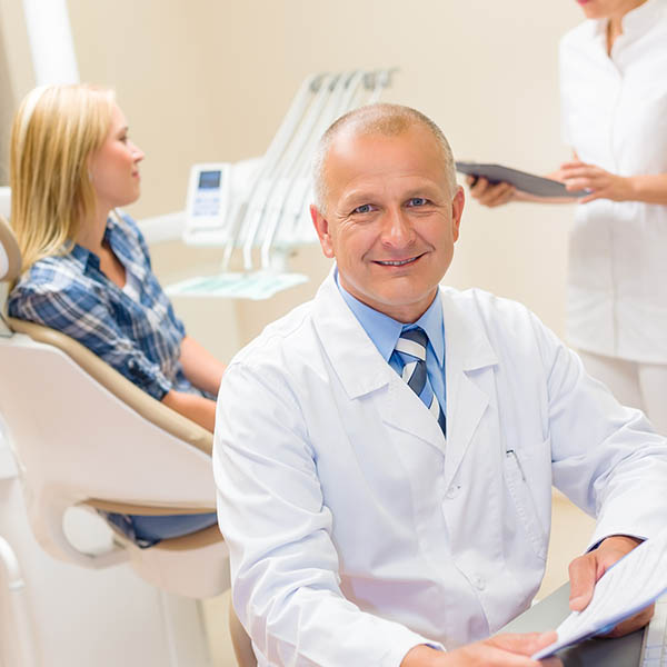 Mature dentist surgeon at office with patient